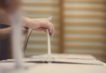 Referendum sulla caccia: la posizione della cabina di regia Referendum sulla caccia: mano deposita urna nella scheda, spalliera di una palestra sullo sfondo