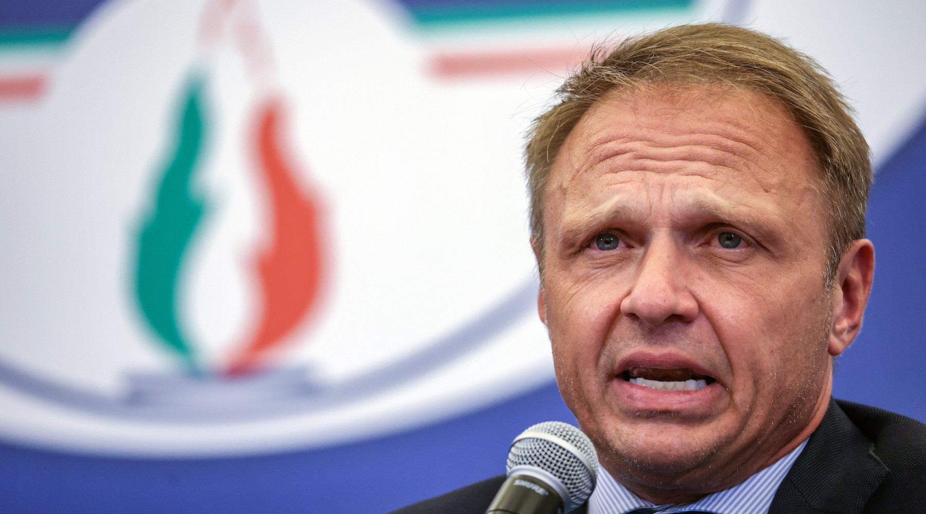 Riforma della legge sulla caccia, Lollobrigida chiede pazienza ai cacciatori Riforma della legge sulla caccia, Lollobrigida chiede pazienza ai cacciatori: Francesco Lollobrigida, ministro dell'Agricoltura, davanti a simbolo di Fratelli d'Italia